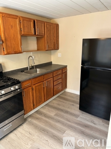 A kitchen with wooden cabinets and a black refrigerator.