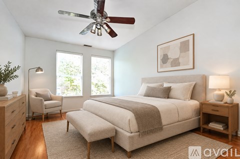A bedroom with a large bed, a chair, and a ceiling fan.