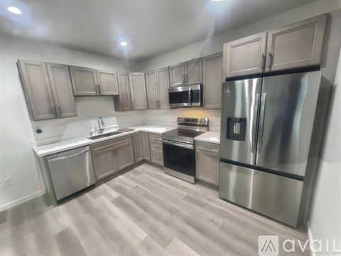 A kitchen with a refrigerator, sink, and cabinets.