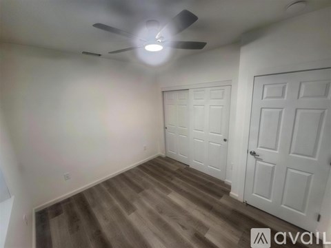 A room with a ceiling fan and two doors.