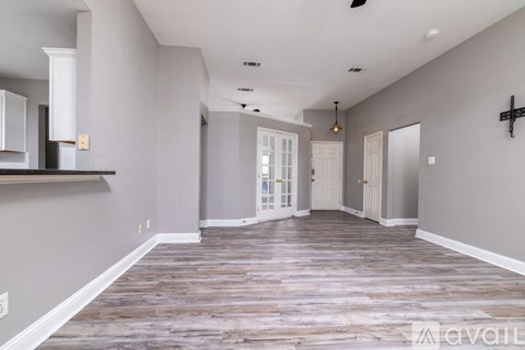 A spacious room with wooden flooring and white walls.