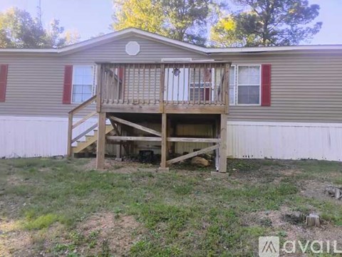 A house with a deck and a tree in the background.