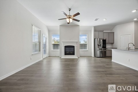 A spacious living room with a fireplace and a ceiling fan.