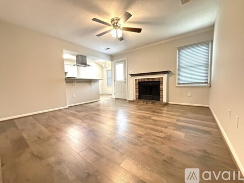 A spacious living room with wood flooring and a fireplace.