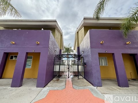 A purple gate leads to a building with yellow doors.