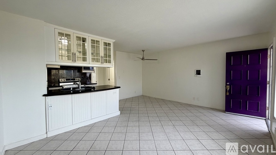 A spacious kitchen with white cabinets and a black countertop.