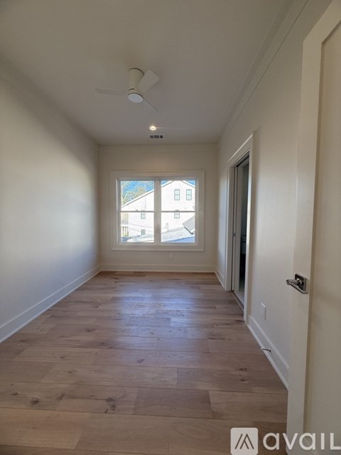 A room with wooden flooring and a window overlooking a building.