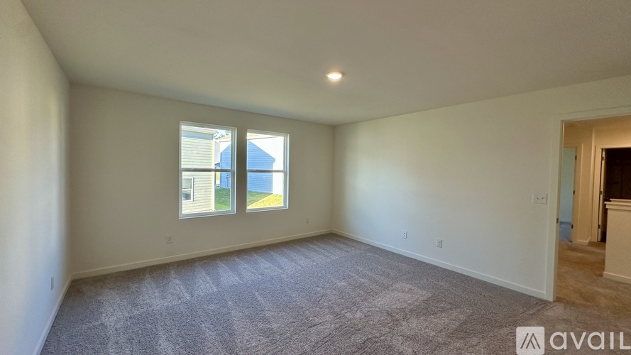 A room with a carpeted floor and a window showing a view of a building.