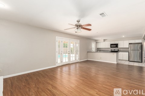 A spacious room with wooden floors and a ceiling fan.
