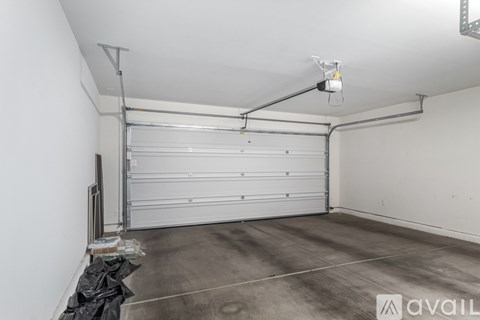 A spacious garage with a closed white door and a black bag on the floor.