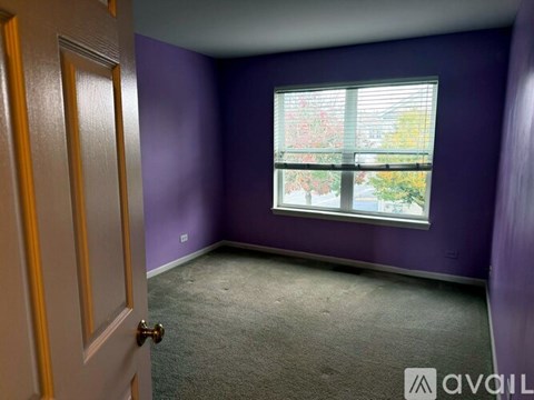 A room with purple walls and a window with a view of trees.