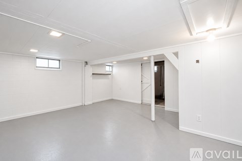 A spacious, empty room with white walls and ceiling, and a window on the left wall.