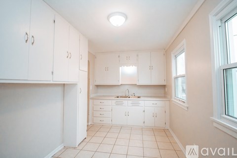 A kitchen with white cabinets and a tiled floor.
