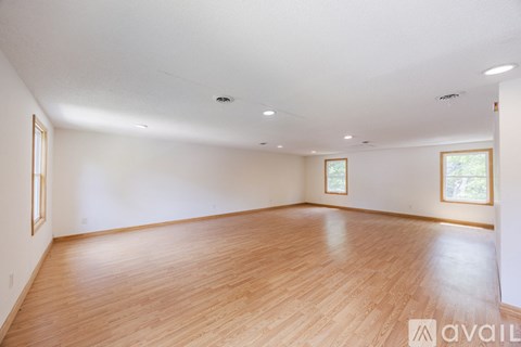 A spacious room with wooden flooring and white walls.