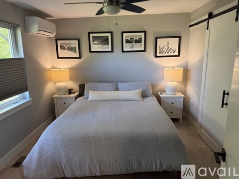 A bedroom with a large bed, two lamps, and three pictures on the wall.
