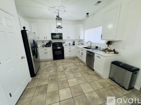 A kitchen with white cabinets and a black fridge.