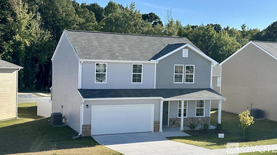 A two-story house with a garage is surrounded by a well-maintained lawn.
