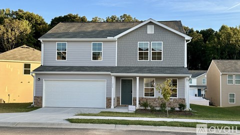 A two-story house with a garage is surrounded by other houses.