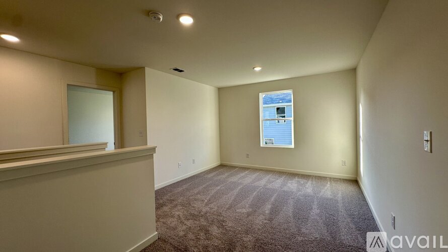 A spacious room with a carpeted floor and a window.
