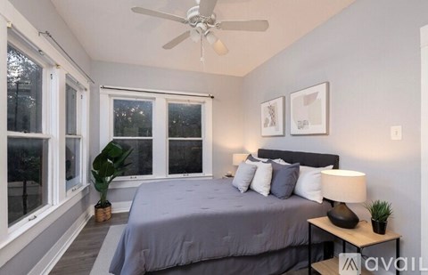 A bedroom with a bed, a ceiling fan, and a window.