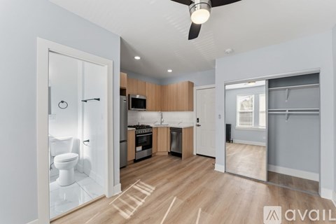A modern kitchen with wooden floors and a ceiling fan.