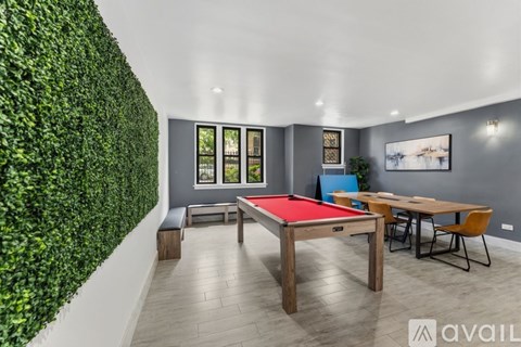 A room with a green hedge wall and a red pool table.