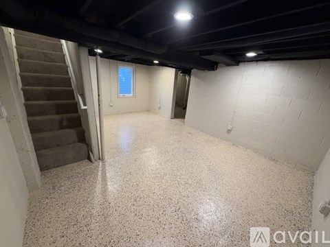 A spacious room with a staircase and a window.