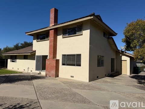 A house with a beige exterior and a red chimney is available for rent.