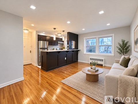 A modern kitchen with wooden floors and a dining area with a white couch.