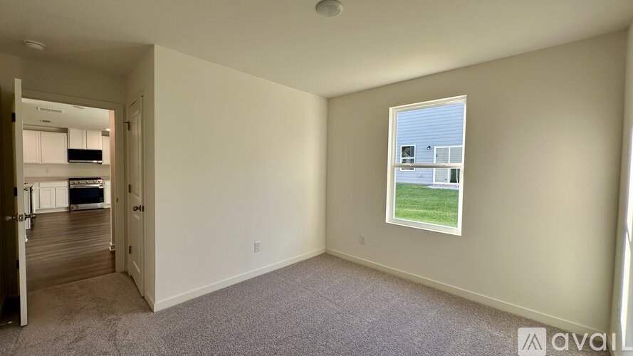 A room with a window showing a view of a green lawn and a building.