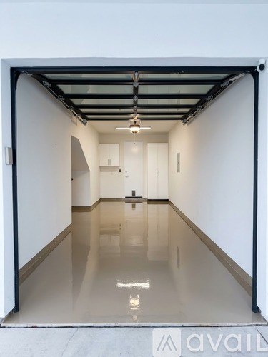 A spacious, empty room with a reflective floor and white walls.