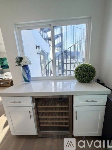 A kitchen with white cabinets and a window overlooking a staircase.