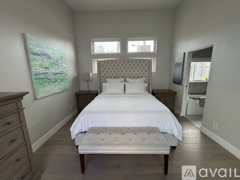 A bedroom with a large bed and a painting on the wall.