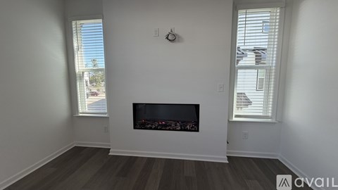 A living room with a fireplace and two windows.