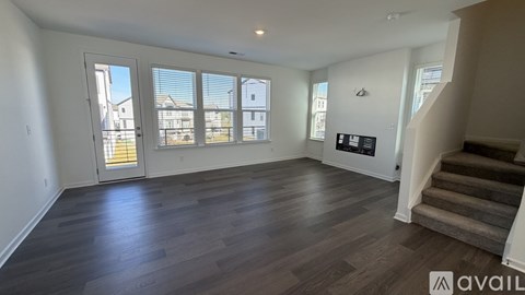 A spacious room with wooden flooring and a staircase leading to another level.