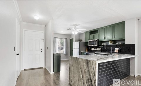 A kitchen with green cabinets and a marble island.