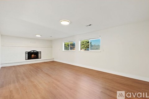 A spacious room with a fireplace and wooden flooring.
