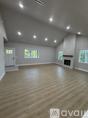 A spacious room with wooden flooring and a fireplace.
