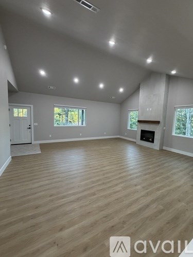 A spacious room with wooden flooring and a fireplace.