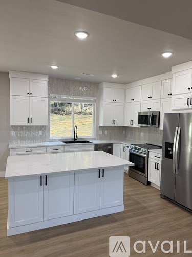 A kitchen with white cabinets and a wooden floor.