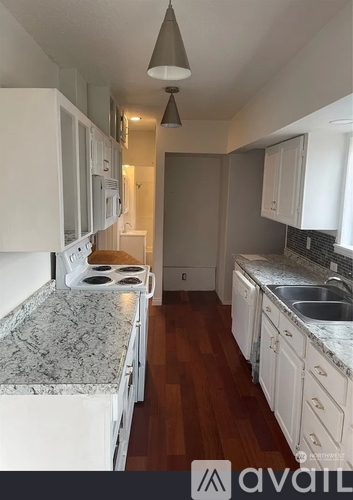 A kitchen with white cabinets and a granite countertop.