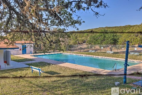 A pool surrounded by a grassy area with a bench and a fence.