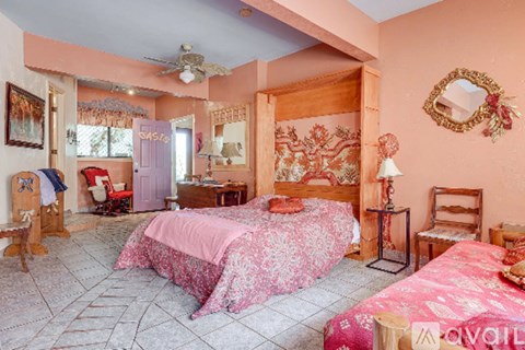 A bedroom with a pink bedspread and a mirror on the wall.