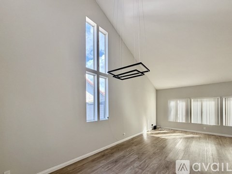 A spacious room with wooden flooring and large windows.