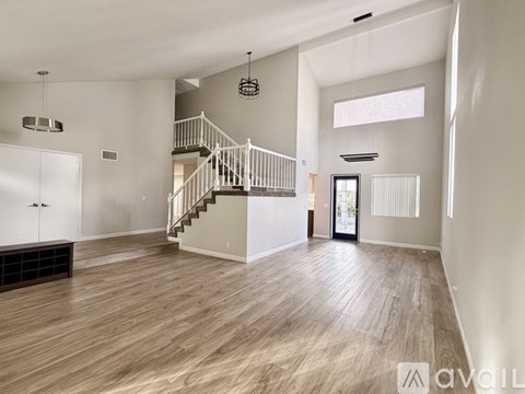 A spacious living room with a staircase and a chandelier.