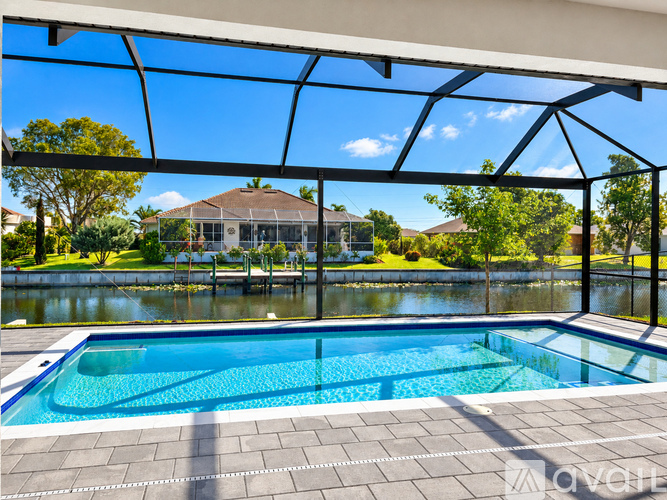 A swimming pool under a glass roof with a house and trees in the background.