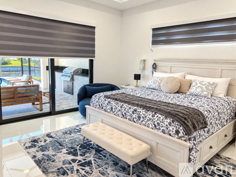 A bedroom with a large bed and a blue ottoman.