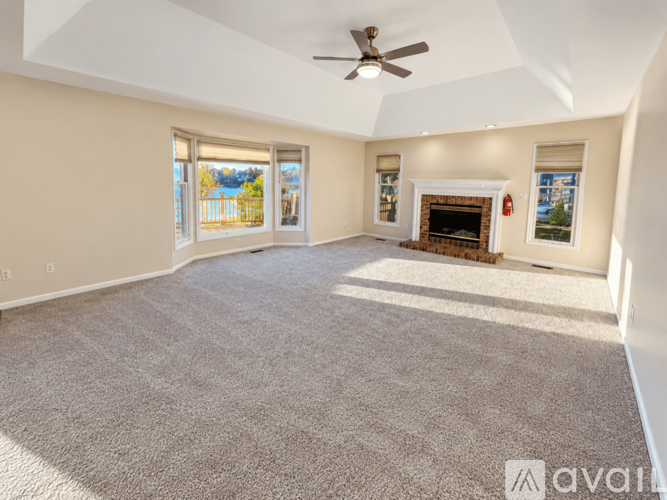 A spacious living room with a fireplace and a ceiling fan.