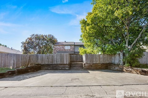 A backyard with a concrete patio and a wooden fence.