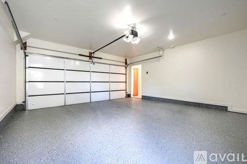 A spacious garage with a closed white door and a light on.